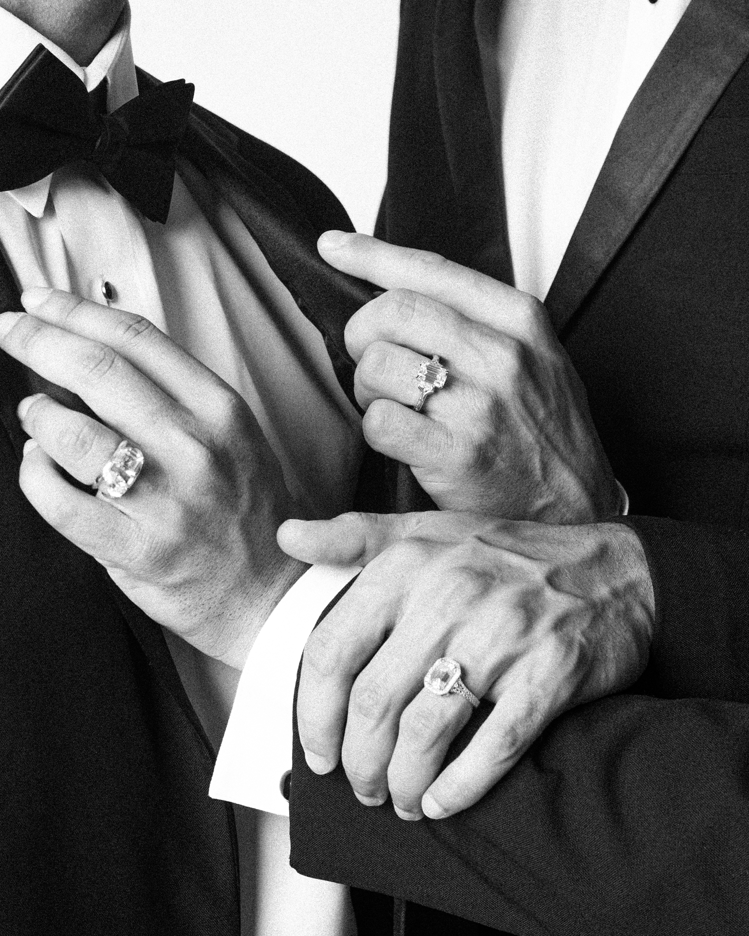 Two hands in tuxedos wearing emerald-cut rings